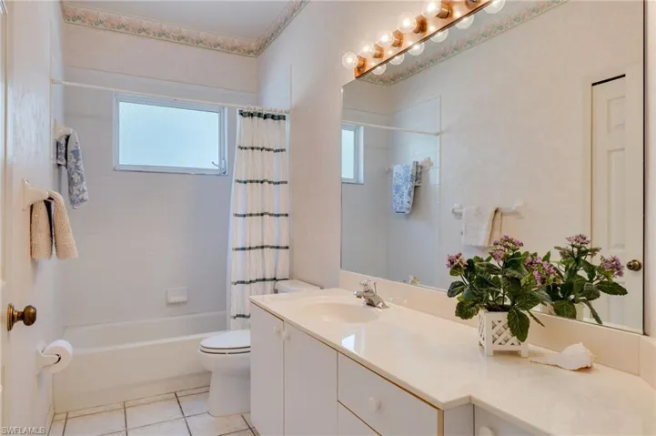 Bathroom with vanity, shower / tub combo with curtain, and light tile patterned floors
