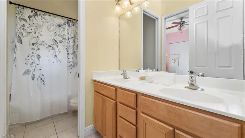 Full bath featuring double vanity, light tile patterned flooring, and shower / bathtub combination with curtain