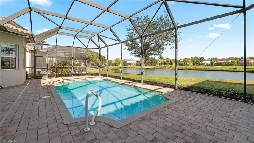Swimming pool featuring a water view, a sunroom, glass enclosure, a patio, and a yard