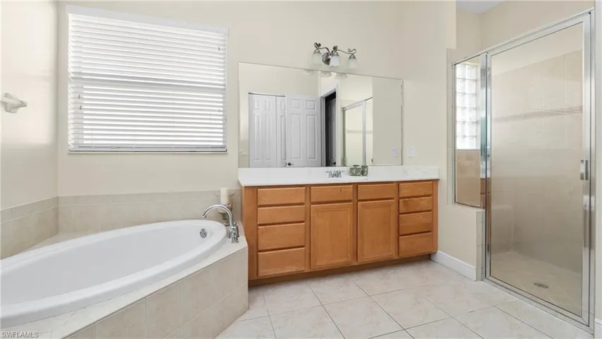 Full bathroom with vanity, a garden tub, a shower stall, and light tile patterned flooring