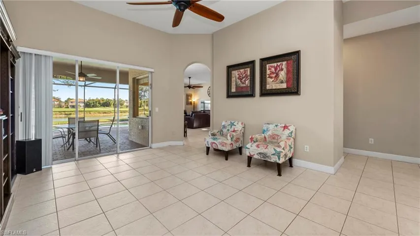 Sitting room with ceiling fan, a water view, light tile patterned floors, arched walkways, and a sunroom