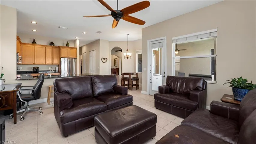 Living room featuring a ceiling fan, light tile patterned flooring, a desk, recessed lighting, and a chandelier