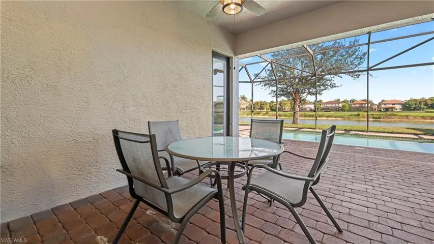 View of patio / terrace featuring an outdoor pool, a water view, glass enclosure, a sunroom, and outdoor dining area