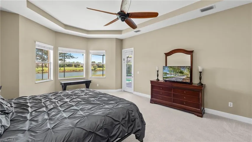 Bedroom featuring a raised ceiling, light colored carpet, access to outside, and ceiling fan