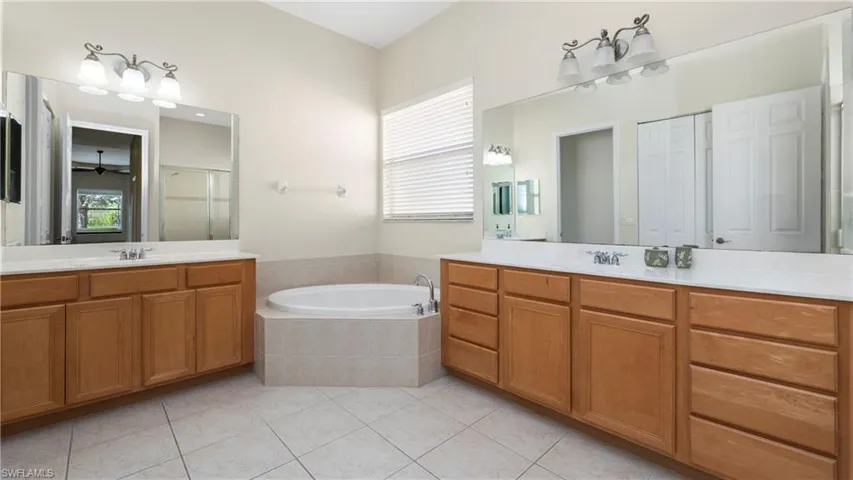 Bathroom with two vanities, healthy amount of natural light, and a garden tub