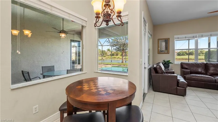 Dining space with ceiling fan, a sunroom, a water view, and tile patterned flooring