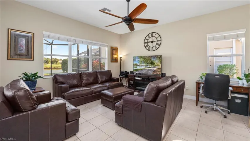 Living area featuring light tile patterned floors, ceiling fan, and plenty of natural light