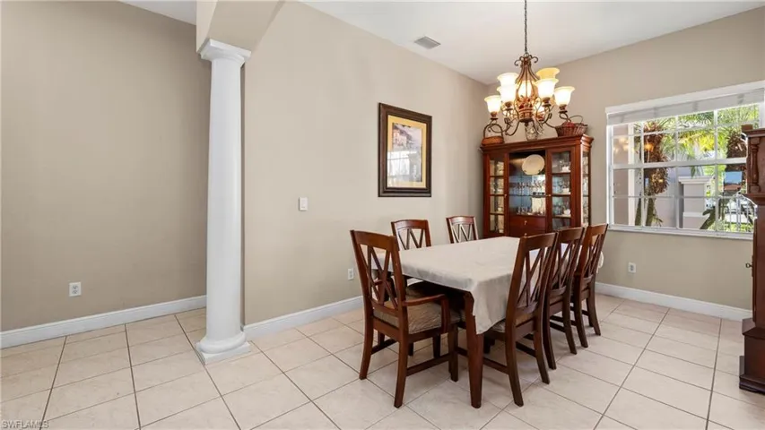 Dining space with ornate columns, light tile patterned flooring, and a chandelier