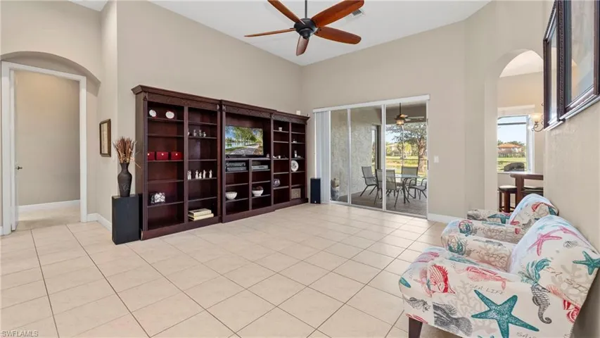Living area with arched walkways, light tile patterned floors, ceiling fan, and a high ceiling