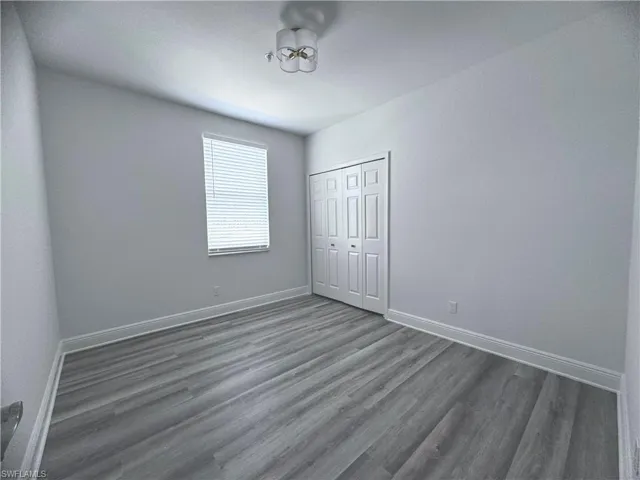 Unfurnished bedroom featuring dark hardwood / wood-style flooring and a closet
