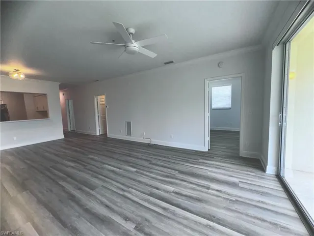 Unfurnished living room with wood-type flooring, ceiling fan, and crown molding