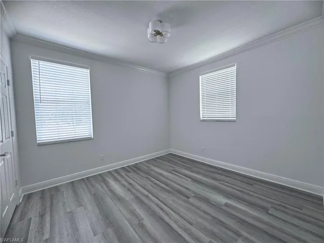 Empty room with dark wood-type flooring and ornamental molding