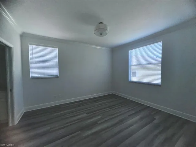 Unfurnished room with dark hardwood / wood-style floors and crown molding