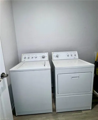 Laundry room featuring washing machine and dryer and hardwood / wood-style flooring