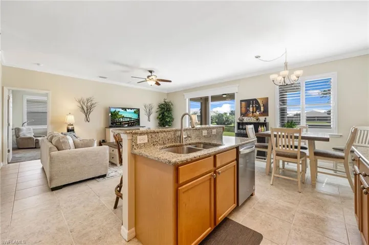 Kitchen featuring a wealth of natural light, sink, hanging light fixtures, stainless steel dishwasher, and a center island with sink