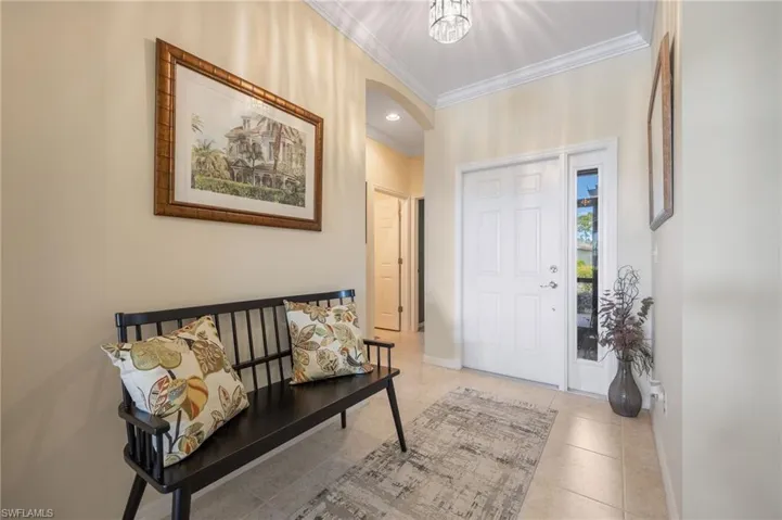 Tiled foyer featuring crown molding