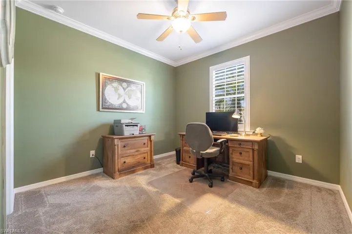 Carpeted 3rd bedroom or home office with crown molding and lit ceiling fan