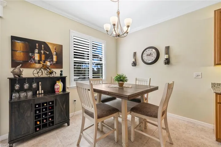 Dining room featuring light tile patterned flooring, plantation shutters, and crown molding