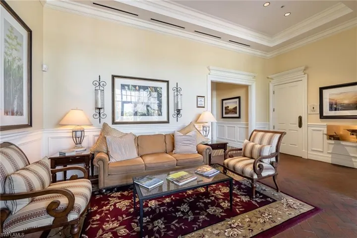 Living room featuring crown molding, a decorative wall, and a wainscoted wall