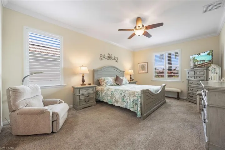 Newer carpeted bedroom with multiple windows, crown molding, and lit ceiling fan