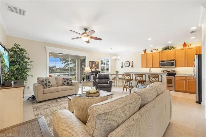 Living room with crown molding, open to kitchen, and light tile floors