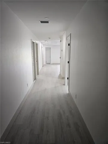 Hallway featuring light wood-type flooring and baseboards