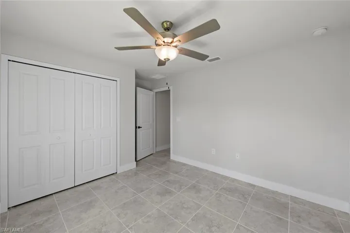 Unfurnished bedroom with a closet, light tile patterned floors, and ceiling fan