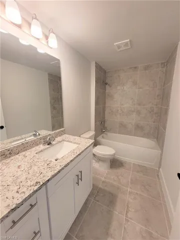 Full bathroom featuring tiled shower / bath combo, tile patterned floors, toilet, and vanity