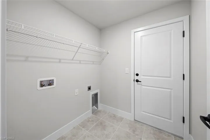Laundry area with light tile patterned flooring, hookup for an electric dryer, and washer hookup
