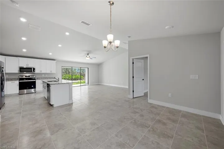 Kitchen with light tile patterned floors, white cabinets, a center island, stainless steel appliances, and hanging light fixtures