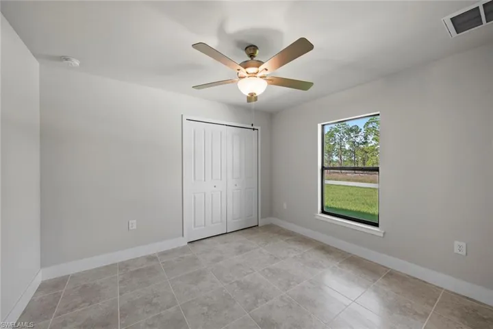 Unfurnished bedroom with light tile patterned flooring, ceiling fan, and a closet