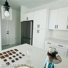 Kitchen with white cabinetry and freestanding refrigerator