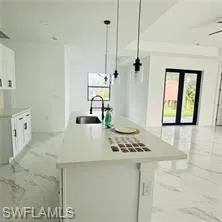 Kitchen with white cabinets, an island with sink, light countertops, and healthy amount of natural light