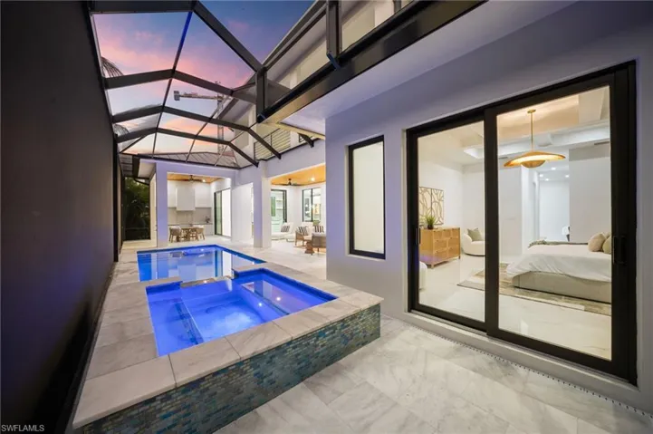 The luxurious primary suite is located on the main level and offers direct access to the pool deck, dual walk-in closets, and a spa-like bath with dual vanities, an oversized walk-in shower with dual entries, and a freestanding soaking tub.