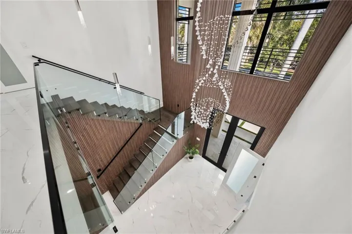 Every detail has been thoughtfully curated—from oversized tile flooring and soaring ceilings with wood beam and shiplap accents to the modern wood-and-glass floating staircase and grand two-story entry foyer.