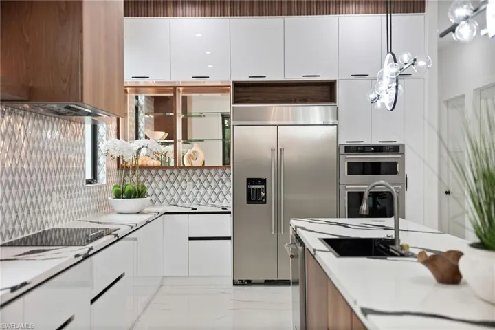 The stunning chef’s kitchen is equipped with quartz countertops, sleek white cabinetry, warm wood accents, and an oversized walk-in pantry.