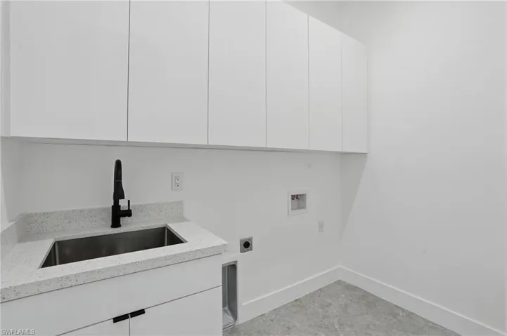 Laundry room with hookup for an electric dryer, hookup for a washing machine, cabinet space, and baseboards