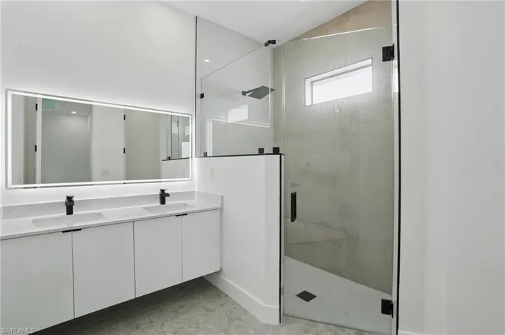 Bathroom featuring a shower stall and double vanity