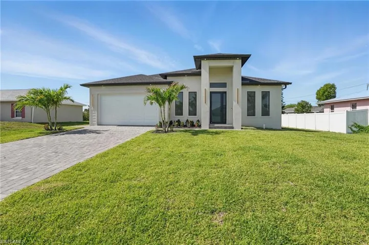 View of front facade with decorative driveway, an attached garage, and stucco siding