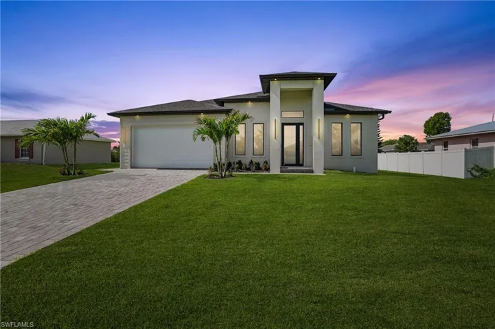 View of front facade with decorative driveway, a garage, and stucco siding