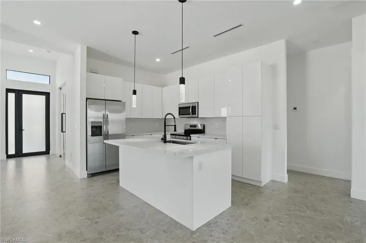 Kitchen featuring appliances with stainless steel finishes, modern cabinets, recessed lighting, a sink, and a center island with sink