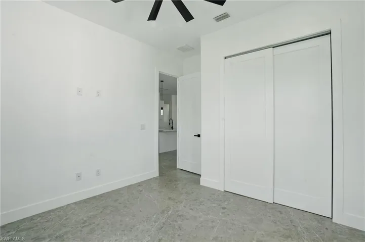 Unfurnished bedroom featuring concrete floors, a closet, baseboards, ceiling fan, and a sink