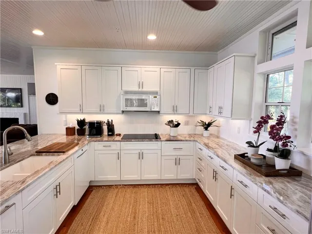 Kitchen with white cabinets, light stone counters, white appliances, recessed lighting, and light wood-style floors