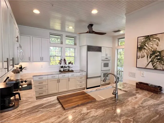 Kitchen with white appliances, white cabinetry, crown molding, ceiling fan, and recessed lighting