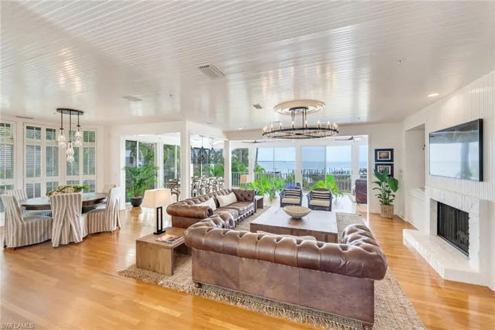 Living area featuring suspended lighting, light wood finished floors, and a fireplace with raised hearth