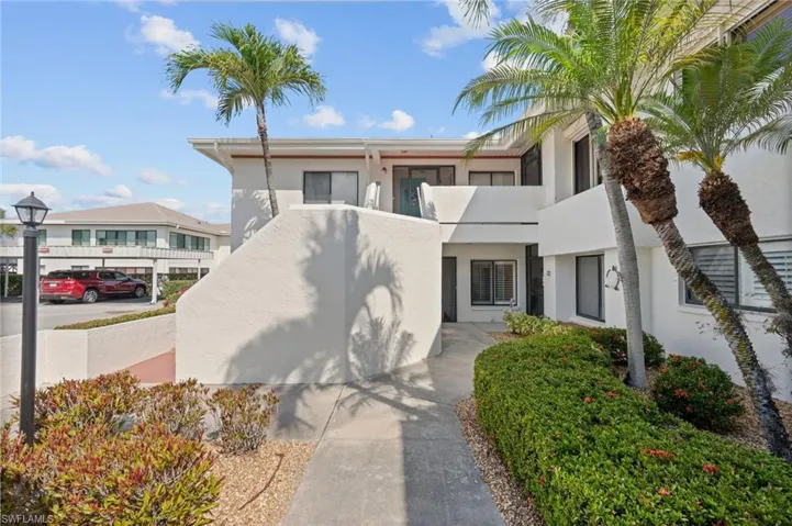 White stucco exterior with multiple windows and mature palm trees