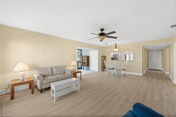 Spacious living and dining areas featuring wood-finish flooring, light neutral wall tones, and crown molding