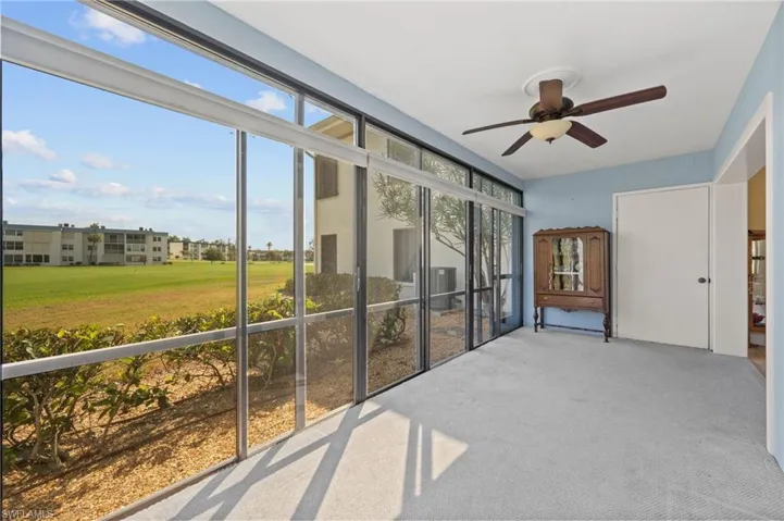 Screened lanai featuring light blue walls, gray carpeting, and a ceiling fan with light fixture