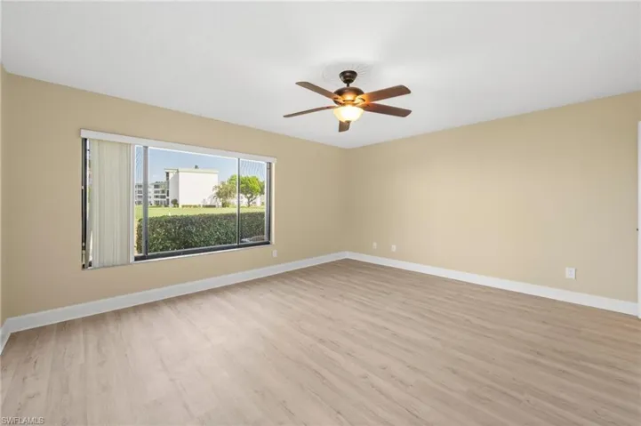 Spacious room featuring wood-finish flooring, light beige walls, and white baseboards