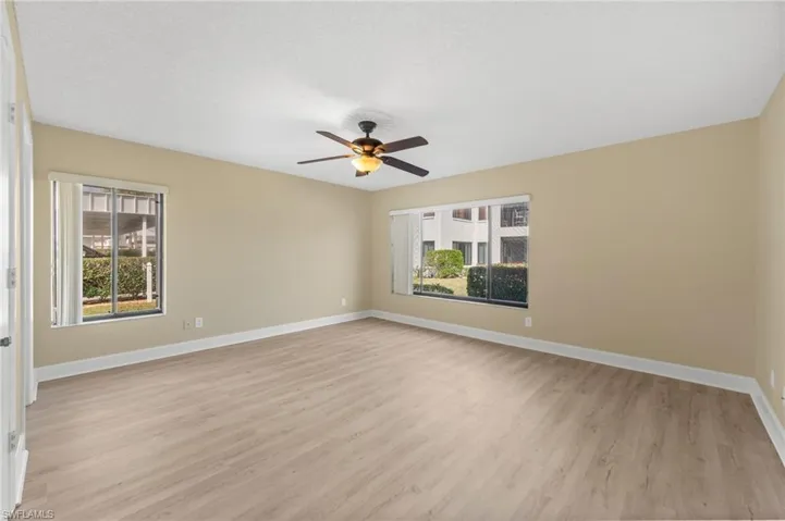 Spacious interior room with wood-finish flooring, neutral wall tones, and white baseboards